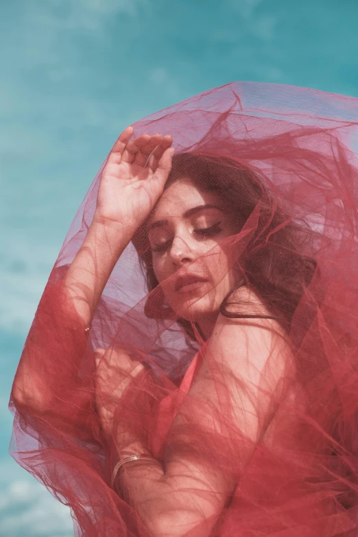 a woman in a red dress with a veil over her head, an album cover, inspired by Elsa Bleda, pexels contest winner, maya ali as a wind mage, diaphanous iridescent silks, red bikini, dreamy soft