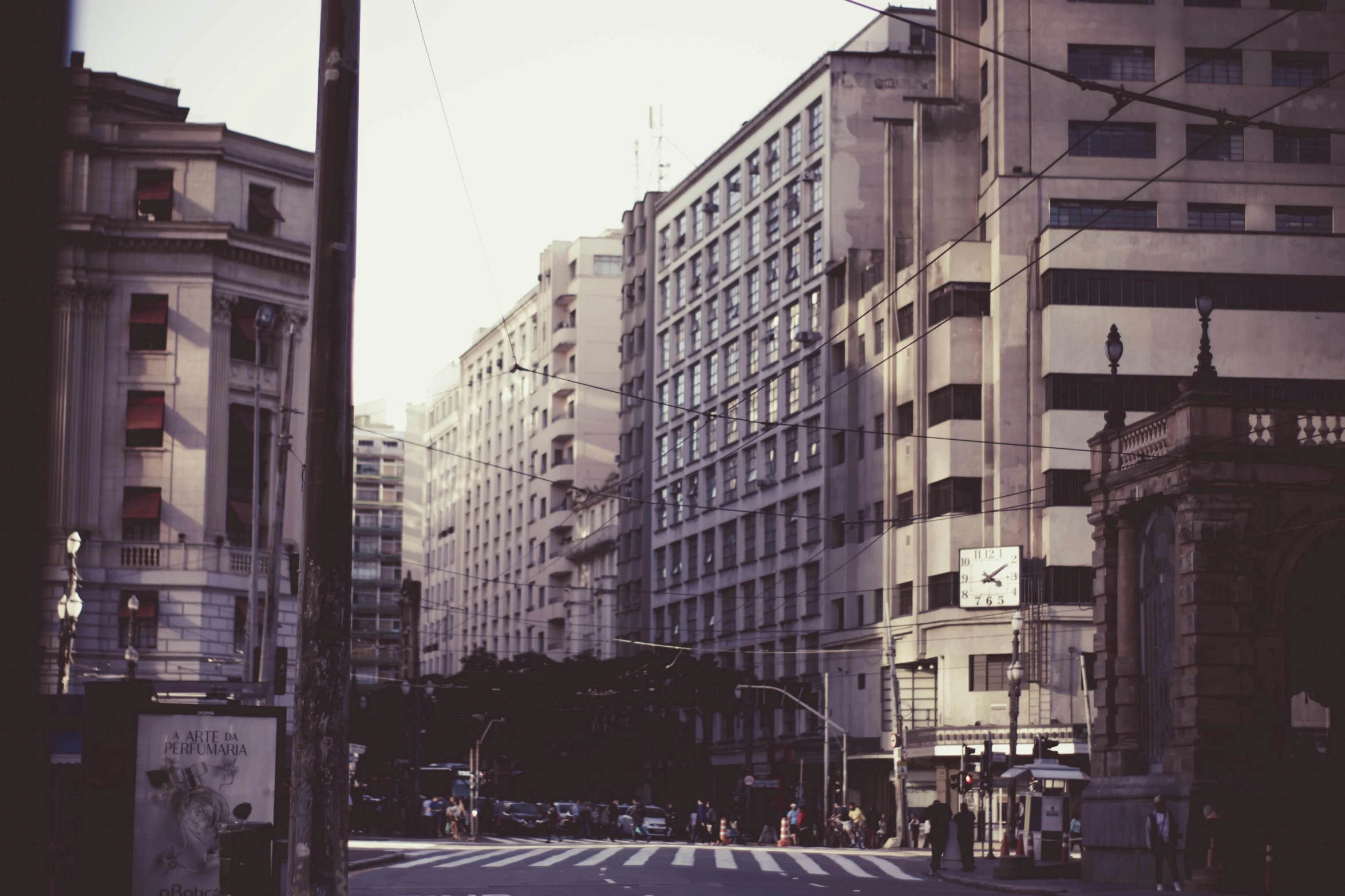 a city street filled with lots of tall buildings, a black and white photo, inspired by Elsa Bleda, unsplash, neoclassicism, faded colors, chile, medium format. soft light, schools