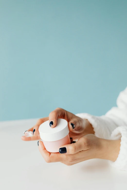 a woman holding a jar of cream on a table, trending on pexels, pastel pink skin tone, from the front, product image, petite