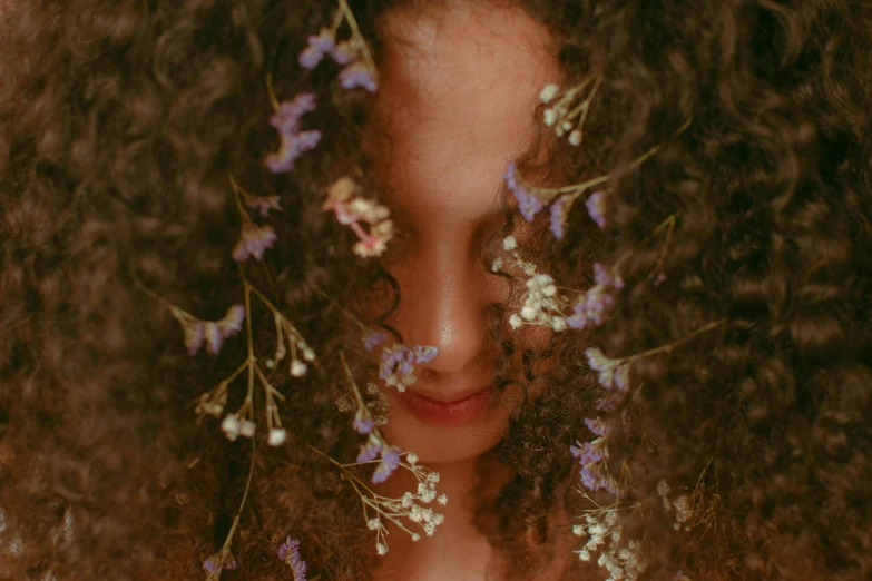 a woman with curly hair and flowers in her hair, inspired by Elsa Bleda, pexels contest winner, hiding, low quality photo, long afro hair, stylized photo