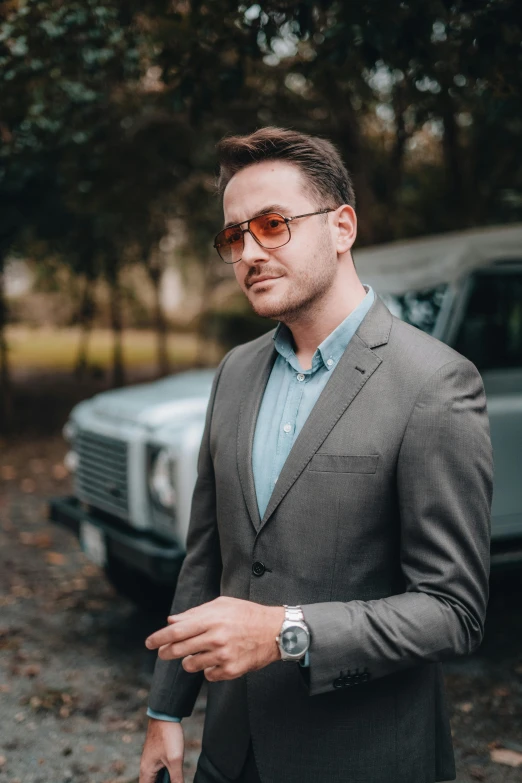 a man in a suit and sunglasses standing in front of a car, a screenshot, by Jacob Toorenvliet, pexels contest winner, wearing business casual dress, instagram picture, portrait shot 8 k, arian mark