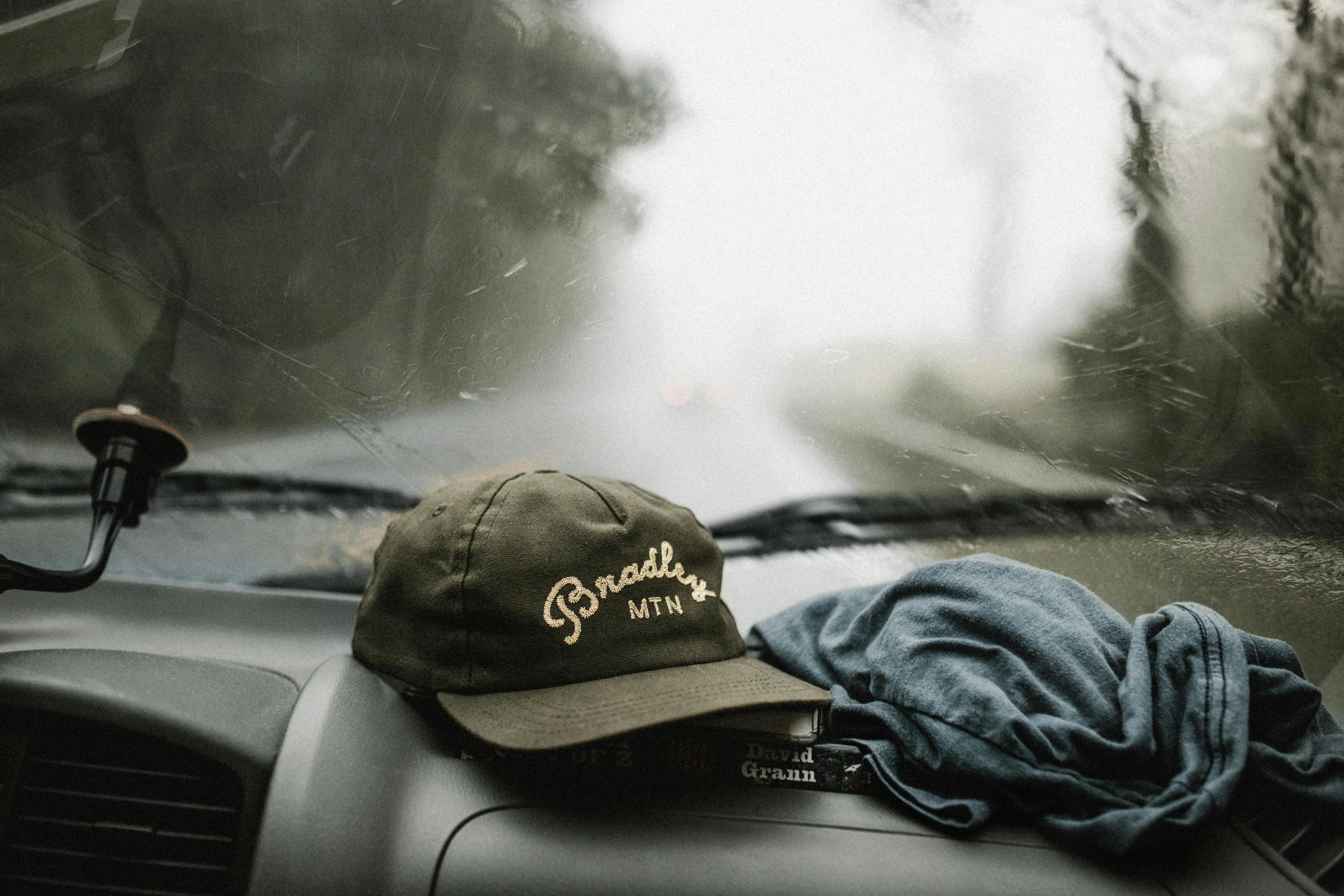 a hat sitting on the dashboard of a car, by Brian Snøddy, drenched clothing, forest green, brad, glory days