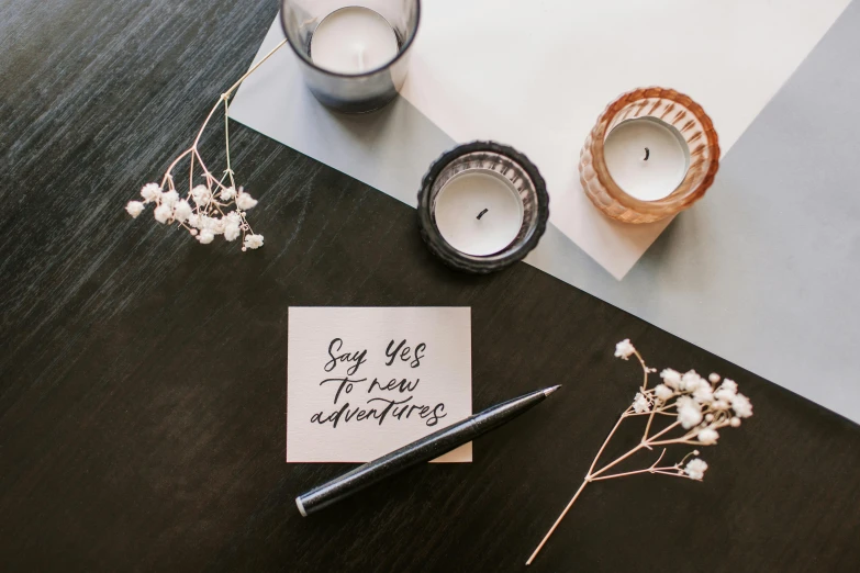 a note sitting on top of a table next to a candle, a still life, unsplash, graffiti, 9 9 designs, white background, invitation card, yes