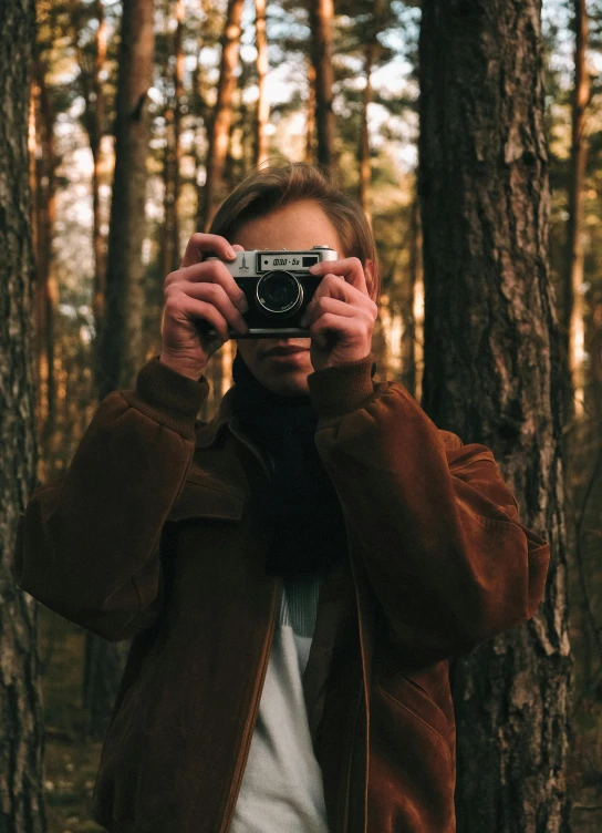 a man taking a picture with a camera in the woods, by Adam Marczyński, vintage aesthetic, full frame image, color photo, photograph