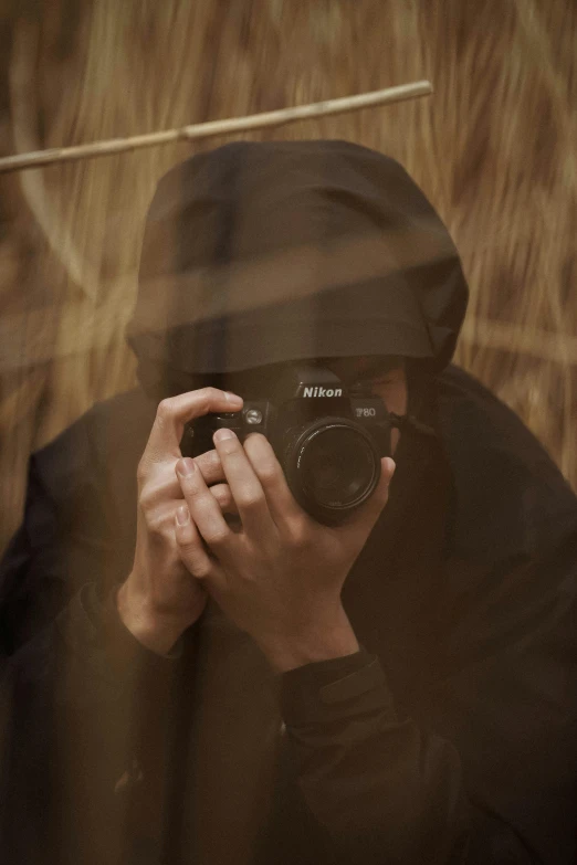 a person taking a picture with a camera, inspired by Steve McCurry, wearing black hooded cloak, **cinematic, ninja, ((sharp focus))