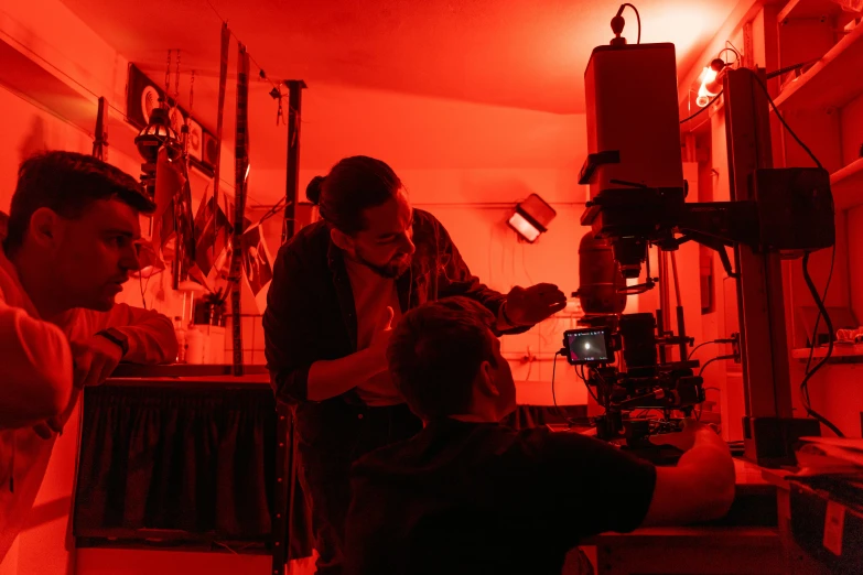 a group of people in a room with a red light, red camera, during the night, maintenance, practical effects