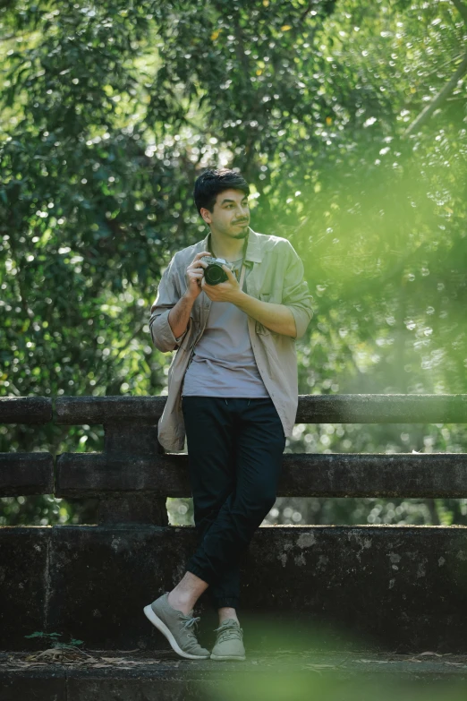 a man sitting on a bench looking at his cell phone, inspired by Adam Dario Keel, sumatraism, greenery, holding a camera, avatar image, asian man