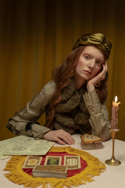 a woman sitting at a table with a candle, an album cover, inspired by Georges de La Tour, renaissance, wes anderson and gucci, eleanor tomlinson, draped in gold, taken in the late 2010s