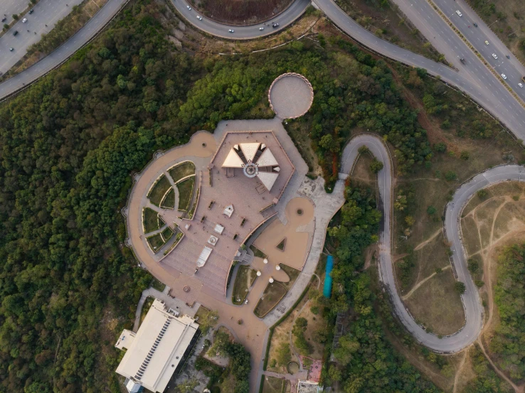 a large building sitting on top of a lush green hillside, an album cover, by Alejandro Obregón, pexels contest winner, dji top down view, space port, parks and public space, shenzhen