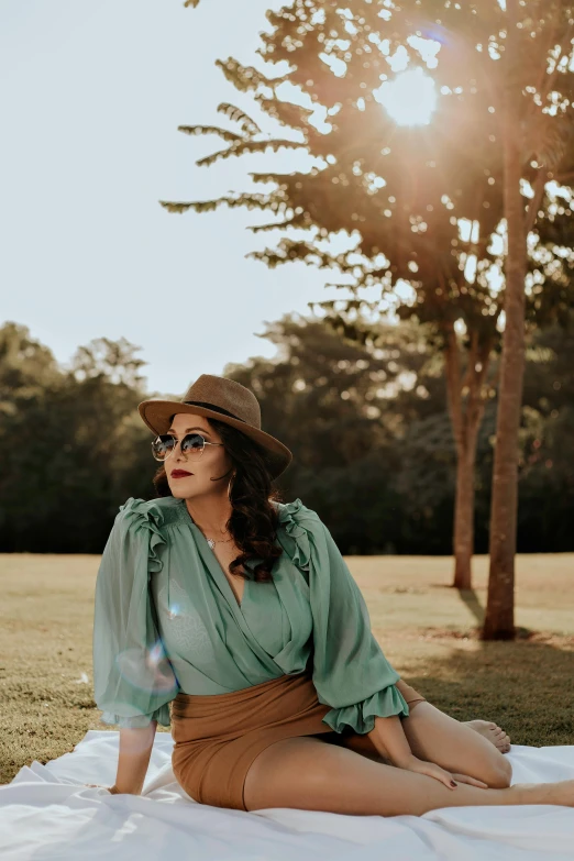 a woman sitting on a blanket in a park, inspired by Elsa Bleda, unsplash, renaissance, wearing sunglasses and a hat, teal suit, southern gothic, plus size woman