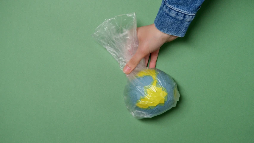 a person holding a plastic bag with a globe in it, modelling clay, slime, half turned around, full product shot