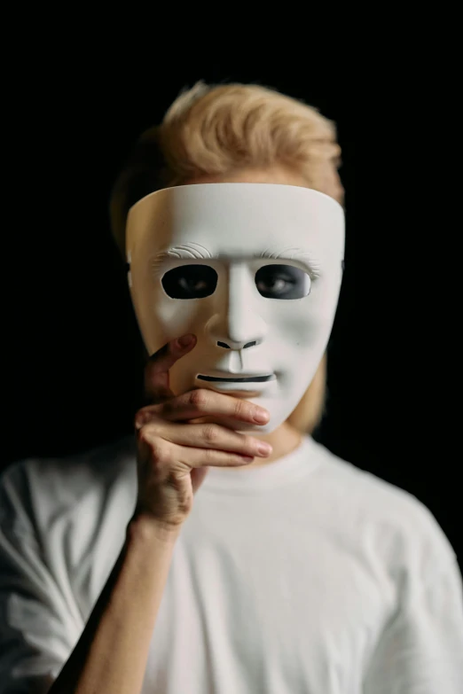 a man with a white mask covering his face, an album cover, trending on pexels, human actress, ( ( theatrical ) ), humanoid face, college