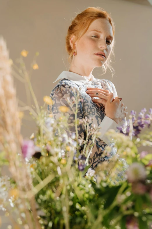 a woman standing in front of a bunch of flowers, by Sara Saftleven, trending on unsplash, renaissance, wearing lab coat and a blouse, brit marling style 3/4, emanating magic from her palms, on a white table