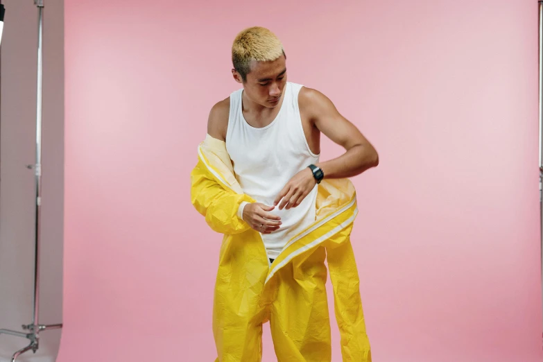 a man in a white tank top and yellow pants, inspired by Russell Dongjun Lu, pexels, plasticien, latex suit and raincoat, healthcare worker, non binary model, worn out clothes