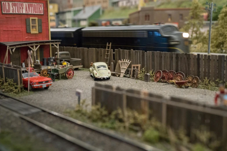 a toy train traveling past a red building, inspired by Christian Krohg, unsplash, photorealism, diorama model, outdoor fairgrounds, miniature of a sports car, 1 9 4 0 setting