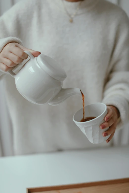 a woman pouring a cup of coffee into a cup, pexels contest winner, wearing a white sweater, teapot : 1, soft shapes, gif