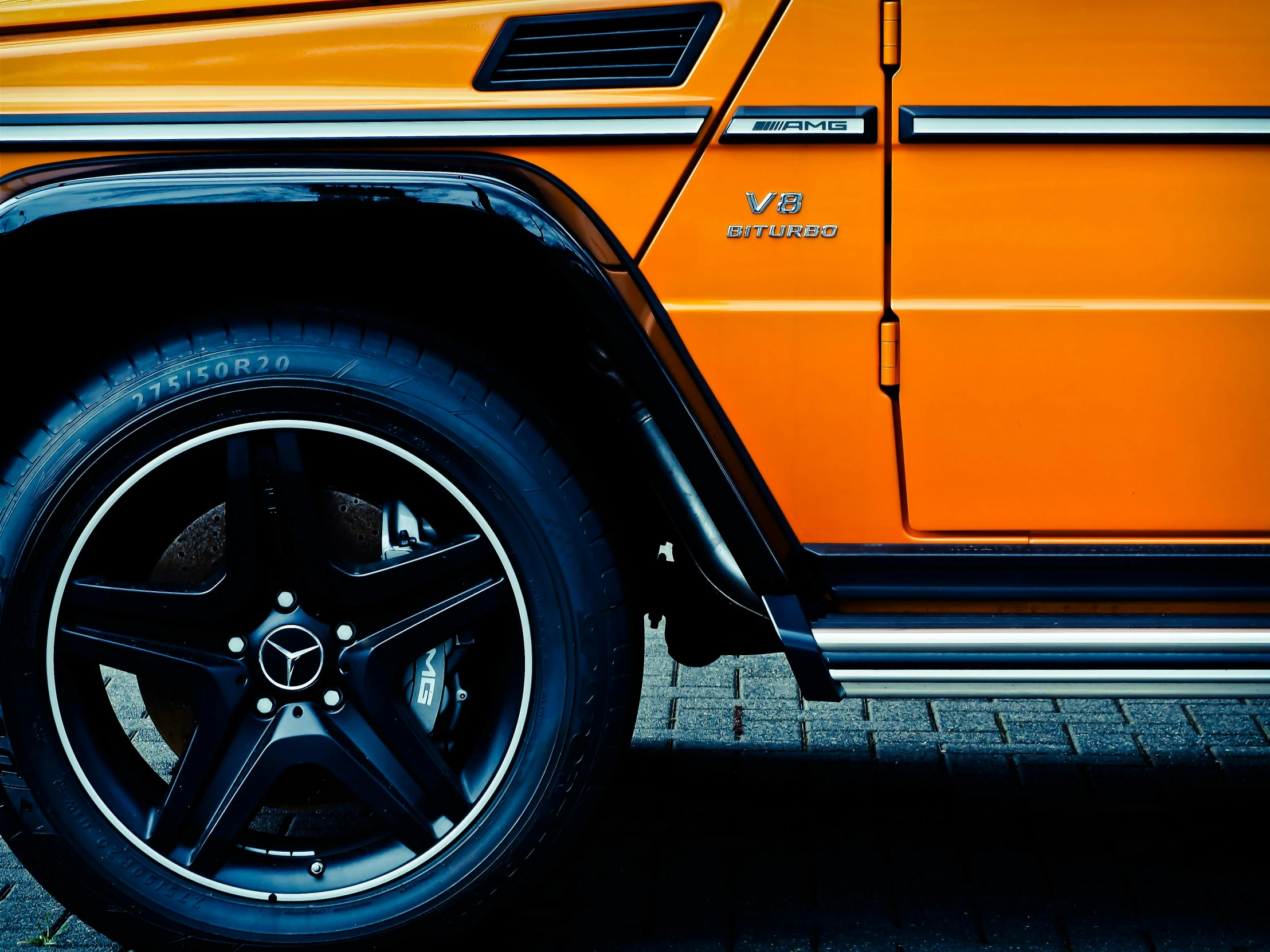 an orange jeep parked on the side of the road, by Thomas Häfner, pexels contest winner, photorealism, detailed alloy wheels, mercedez benz, black and orange colour palette, dynamic closeup