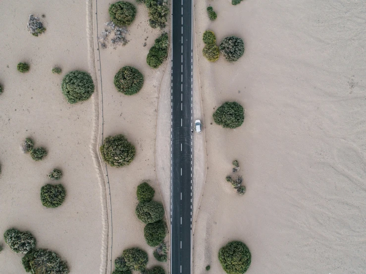 an aerial view of a road next to a body of water, by Jacob Toorenvliet, pexels contest winner, crossing the desert, no trees, one car, floods