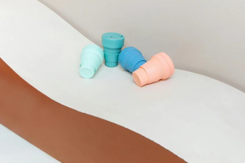 a couple of rolls of toilet paper sitting on top of a toilet, inspired by Rachel Whiteread, unsplash, plasticien, blueberry and orange and teal, silicone cover, coffee cups, earthy light pastel colours