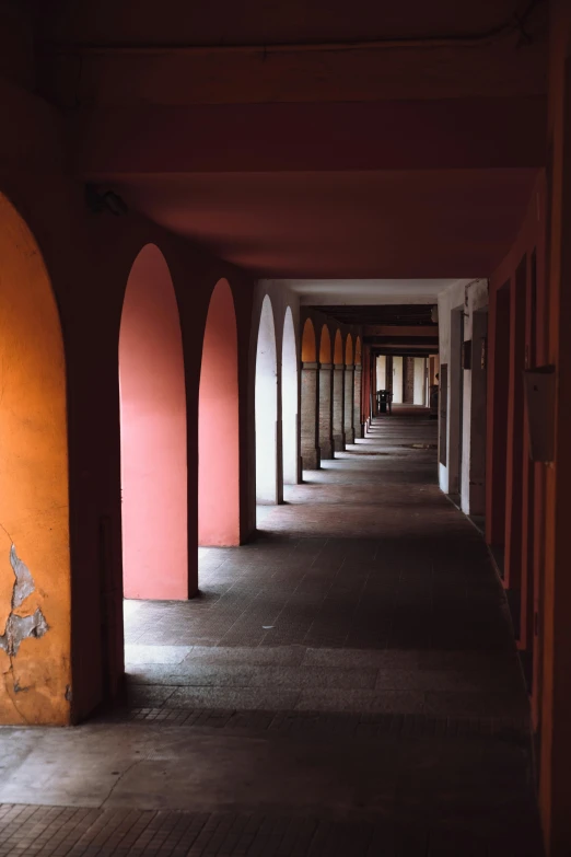 a long hallway with orange walls and arches, inspired by Luis Paret y Alcazar, unsplash contest winner, pink concrete, barracks, kalighat, taken with sony alpha 9