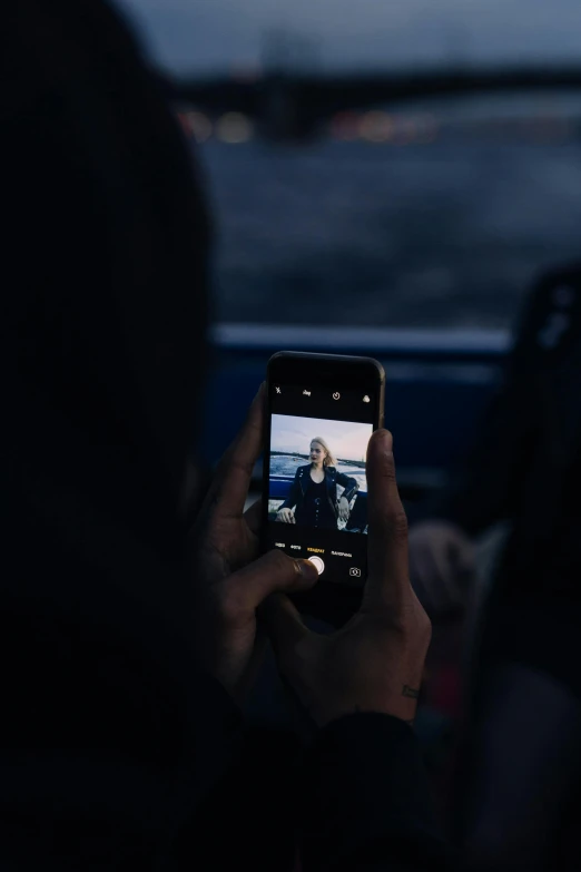 a person taking a picture with a cell phone, dark, on a boat, trending on vsco, iceland photography