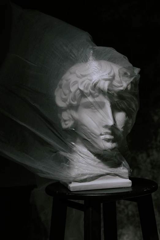 a statue sitting on top of a wooden stool, a marble sculpture, inspired by Antonio Canova, unsplash contest winner, classical realism, wearing translucent veils, dressed in plastic bags, dark portrait of medusa, still from a music video