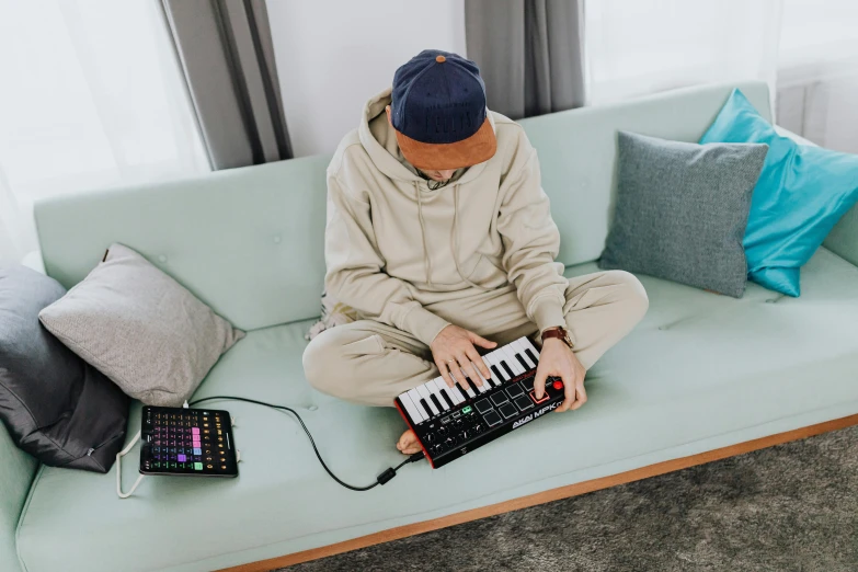 a person sitting on a couch with a keyboard, wearing a tracksuit, audio equipments, avatar image, instagram photo