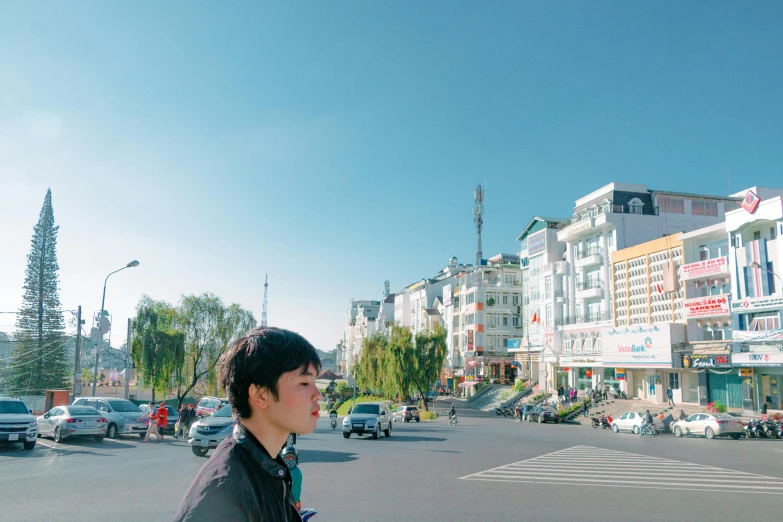 a man standing in the middle of a street, an album cover, by Jin Nong, unsplash, realism, clear blue sky, zezhou chen, town center background, male ulzzang