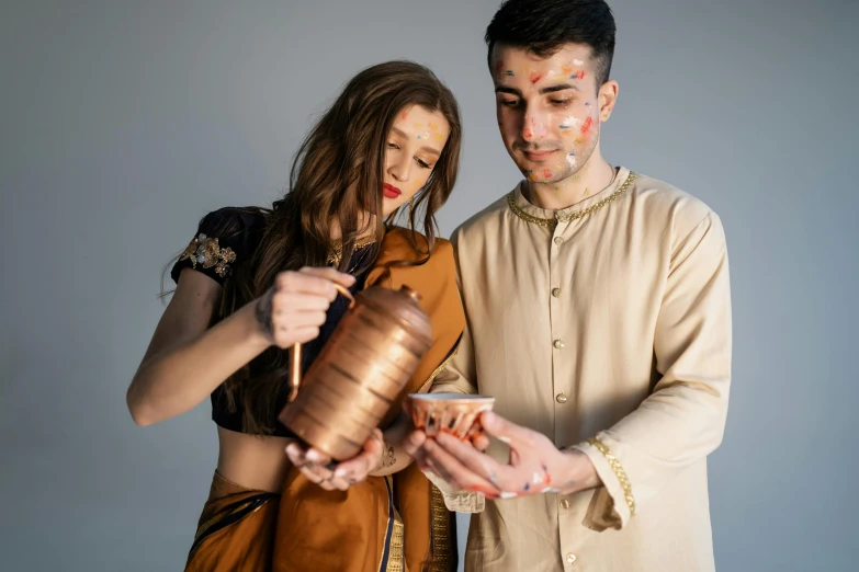 a man and a woman standing next to each other, trending on pexels, renaissance, copper cup, wearing a kurta, cosplay photo, pouring