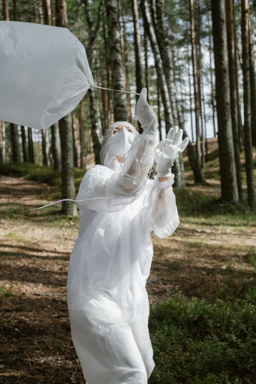 a person in a white suit holding an umbrella, inspired by Marina Abramović, unsplash, interactive art, tardigrade statue in the forest, flight suit and gloves, balloons, funeral veil