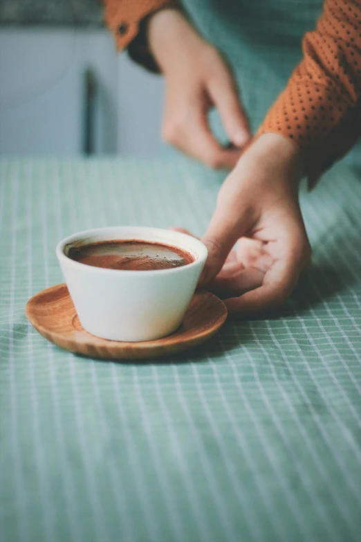 a person holding a cup of coffee on a table, square, jen atkin, vintage color, chocolate