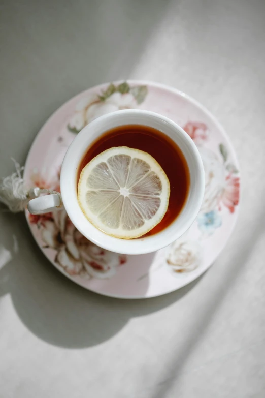 a cup of tea with a slice of lemon on a saucer, a picture, trending on pexels, renaissance, how pretty, kailee mandel, lolita, round-cropped