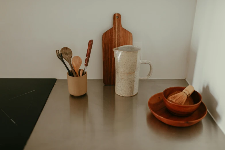 a kitchen counter topped with wooden utensils, trending on unsplash, background image, white mug, low quality photo, stainless steal