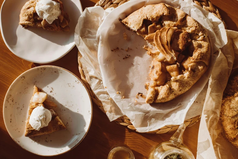 a wooden table topped with plates of food, a photo, by Emma Andijewska, trending on unsplash, renaissance, apple pie, parchment paper, background image