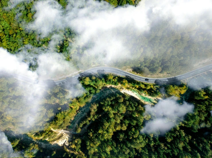 an aerial view of a winding road surrounded by trees, a matte painting, pexels contest winner, floating lands in-clouds, sichuan, aerial, ultrawide lens”