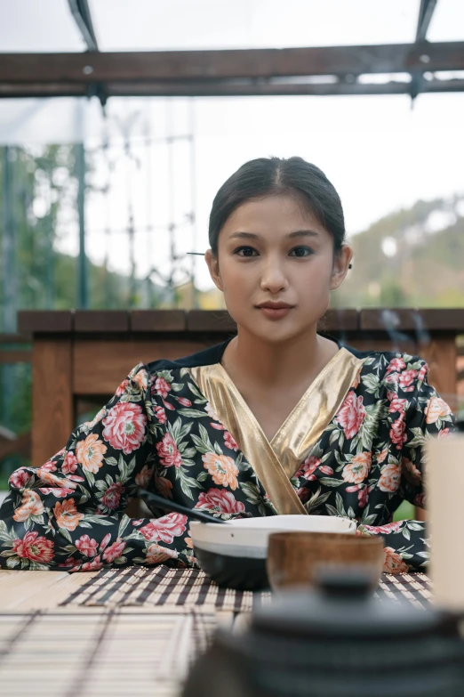 a woman sitting at a table with a plate of food, inspired by Zhang Yin, sumatraism, looking serious, young himalayan woman, still frame from a movie, wearing robe