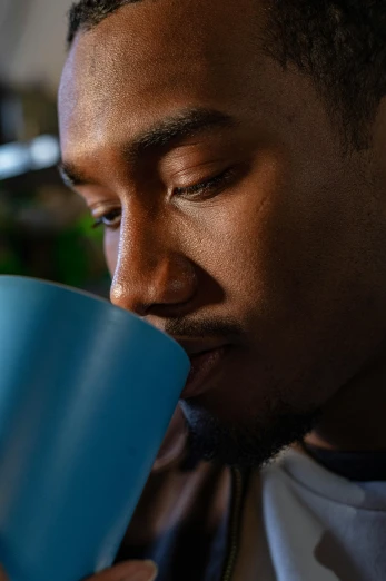 a man drinking out of a blue cup, by Paul Davis, pexels contest winner, dark skinned, exhausted face close up, ashteroth, 8k resolution. tupac