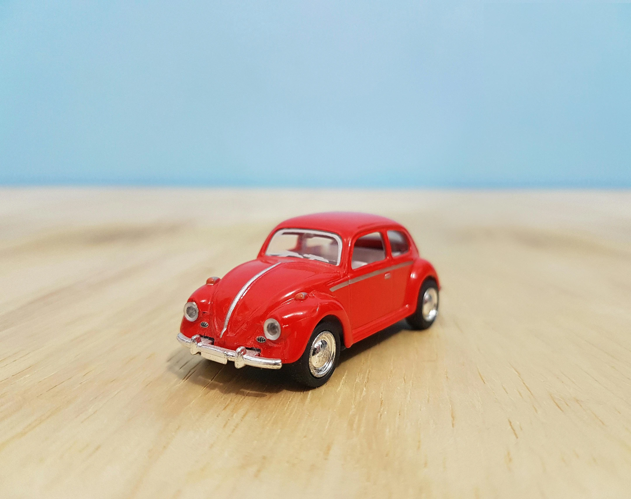 a red toy car sitting on top of a wooden table, pexels contest winner, photorealism, beetle, hyperreal highly detailed 8 k, action figurine toy, animation model