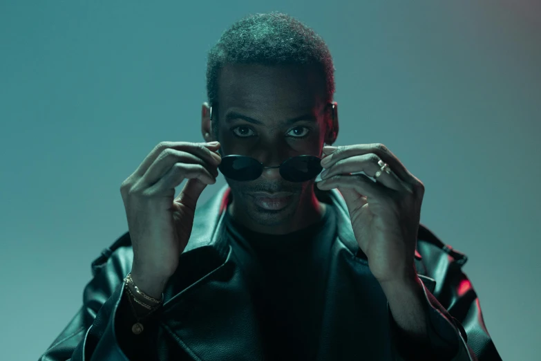 a man in a leather jacket holding a pair of glasses, an album cover, inspired by Theo Constanté, pexels contest winner, grime, luts, new album cover, performing a music video