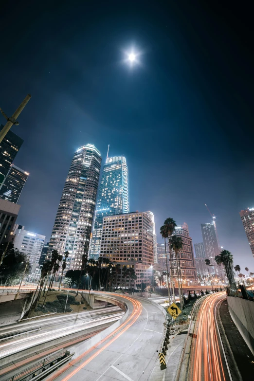 a city at night with a full moon in the sky, a picture, by Ryan Pancoast, unsplash contest winner, los angeles ca, 8k resolution”, streetlights, tall skyscrapers