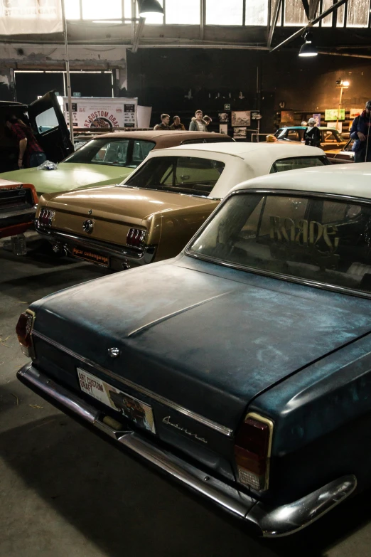 a group of old cars parked in a garage, lit from behind, displayed in the exhibition hall, melbourne, lowrider crash test