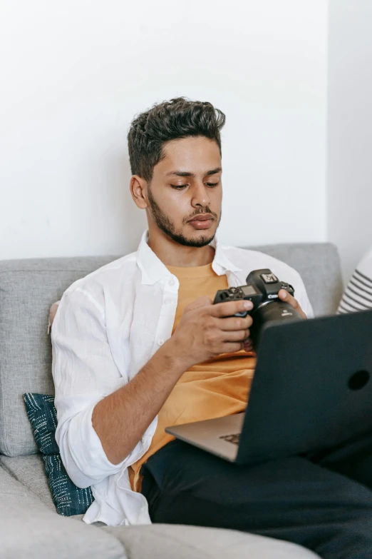 a man and woman sitting on a couch looking at a laptop, by Cosmo Alexander, pexels contest winner, holding a big camera, young spanish man, portrait of danny gonzalez, young man with medium - length