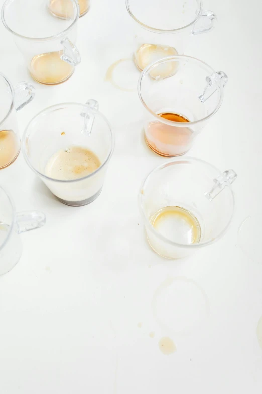 a bunch of cups that are sitting on a table, a still life, by Nina Hamnett, process art, raw egg yolks, vanilla smoothie explosion, on a white background, transparent liquid