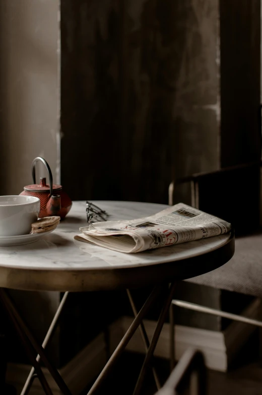 a table with a cup of coffee and a newspaper on it, a portrait, by Daniel Gelon, private press, rustic setting, while marble, archviz, 15081959 21121991 01012000 4k