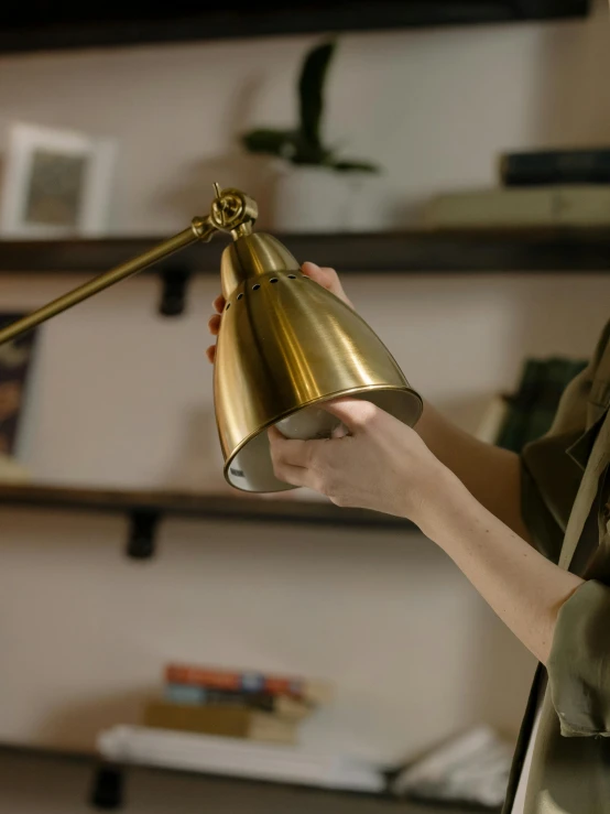 a woman that is holding a lamp in her hand, unsplash, happening, brass equipment and computers, detailed product image, lit from the side, detail shot