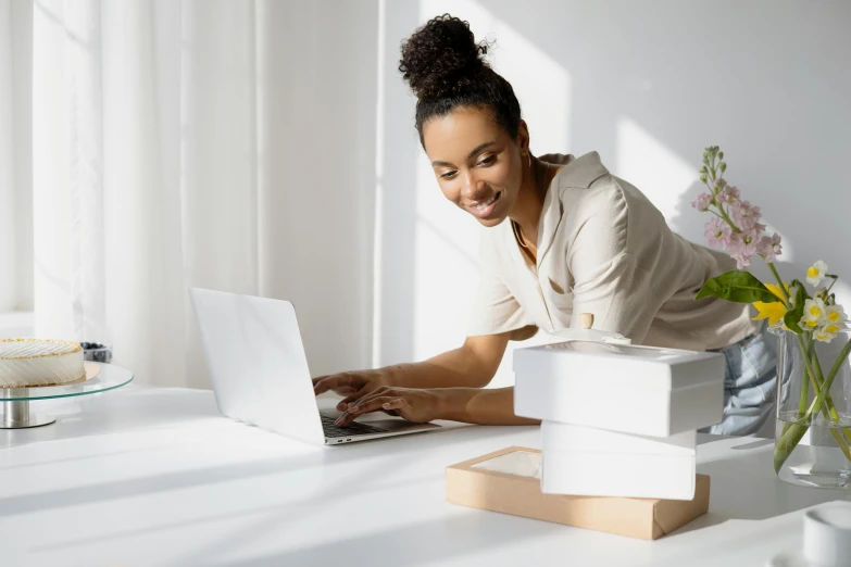 a woman sitting at a table working on a laptop, by Eden Box, brown and white color scheme, excited, stacked image, white box