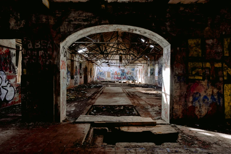 an old run down building with graffiti all over it, inspired by Thomas Struth, steel archways, lpoty, 1980s photograph, ((rust))