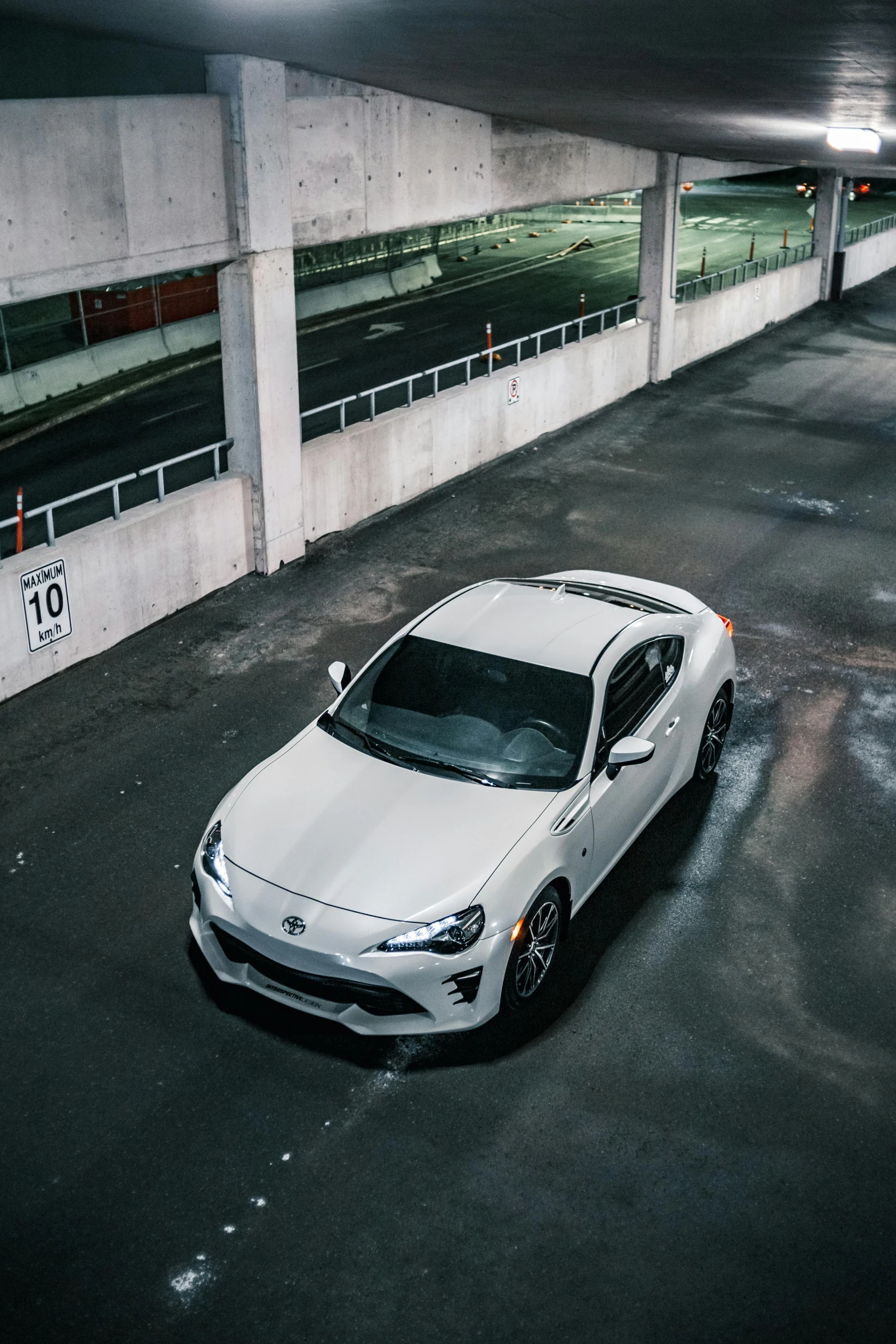 a white car parked in a parking garage, inspired by Kanō Shōsenin, unsplash contest winner, renaissance, soft top roof raised, trimmed with a white stripe, white and grey, front and center