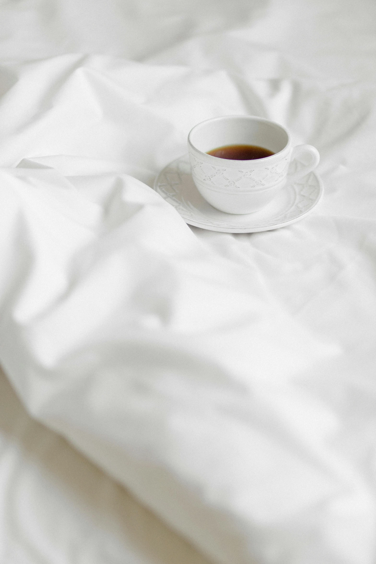 a cup of coffee sitting on top of a bed, fine art, white sheets, detailed product image, detail shot, bedhead