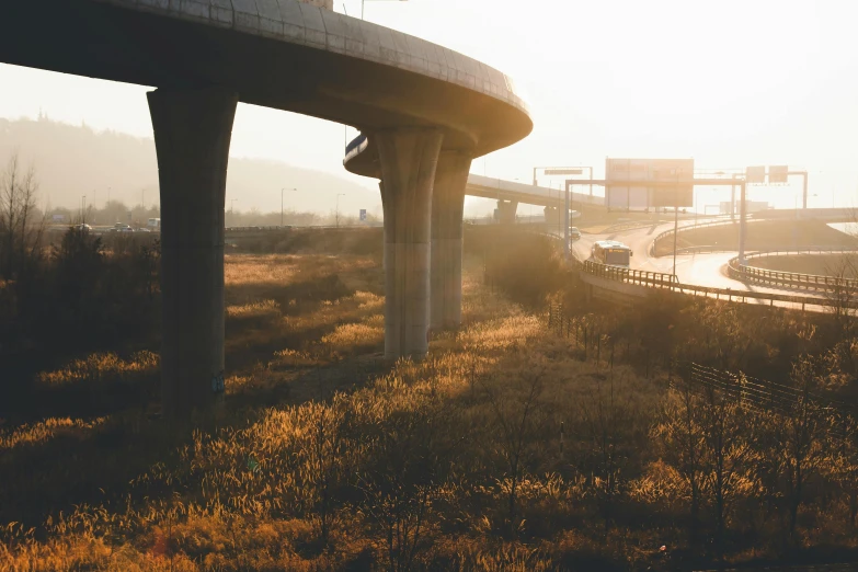 a view of a highway with a bridge in the background, a matte painting, unsplash contest winner, brutalism, golden hour 8 k, metal towers and sewers, instagram photo, flat curves